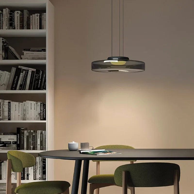 Smoke grey glass pendant light over a black table beside a bookshelf