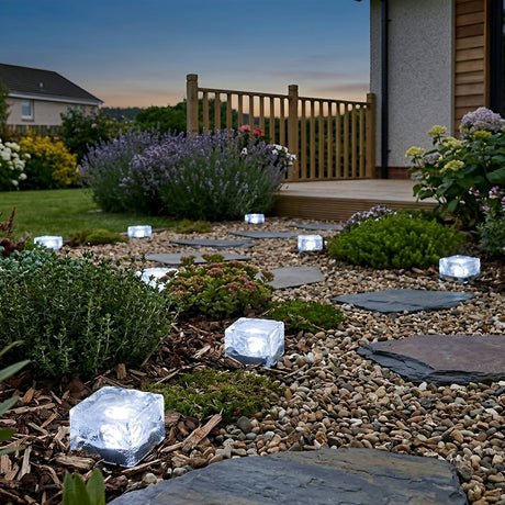 White cube lights edging a gravel border in a suburban back garden at dusk