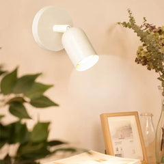 Solid colour bedside wall sconce shown from the front with lit shade