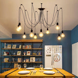 Spider chandelier with long cables lit above a dining table in a blue room