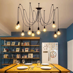 Spider chandelier with long cables lit above a dining table in a blue room