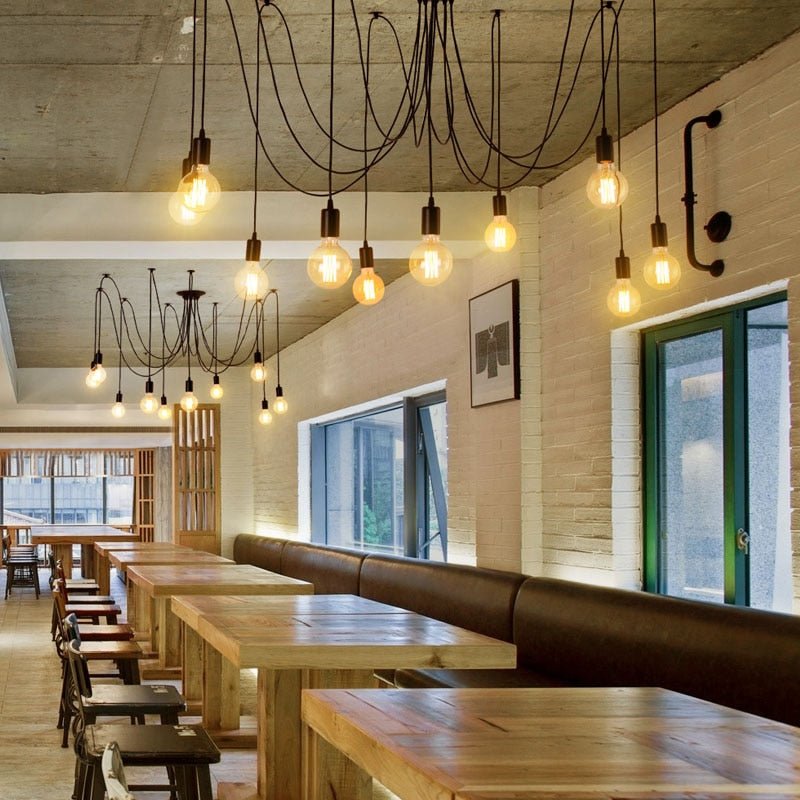 Two spider chandeliers lit above long tables in a restaurant