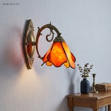 Lit orange petal sconce beside a wood side table with a vase and books