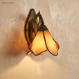 Cream and peach glass petal sconce casting a warm downward glow on plaster