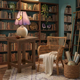 Moon motif glass lamp on a side table in a green library with rattan chair