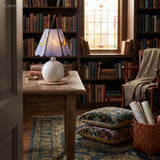 Stained glass lamp glowing on a timber table in front of a leaded window