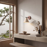 Stone cone wall light glowing beside a bright window and plants