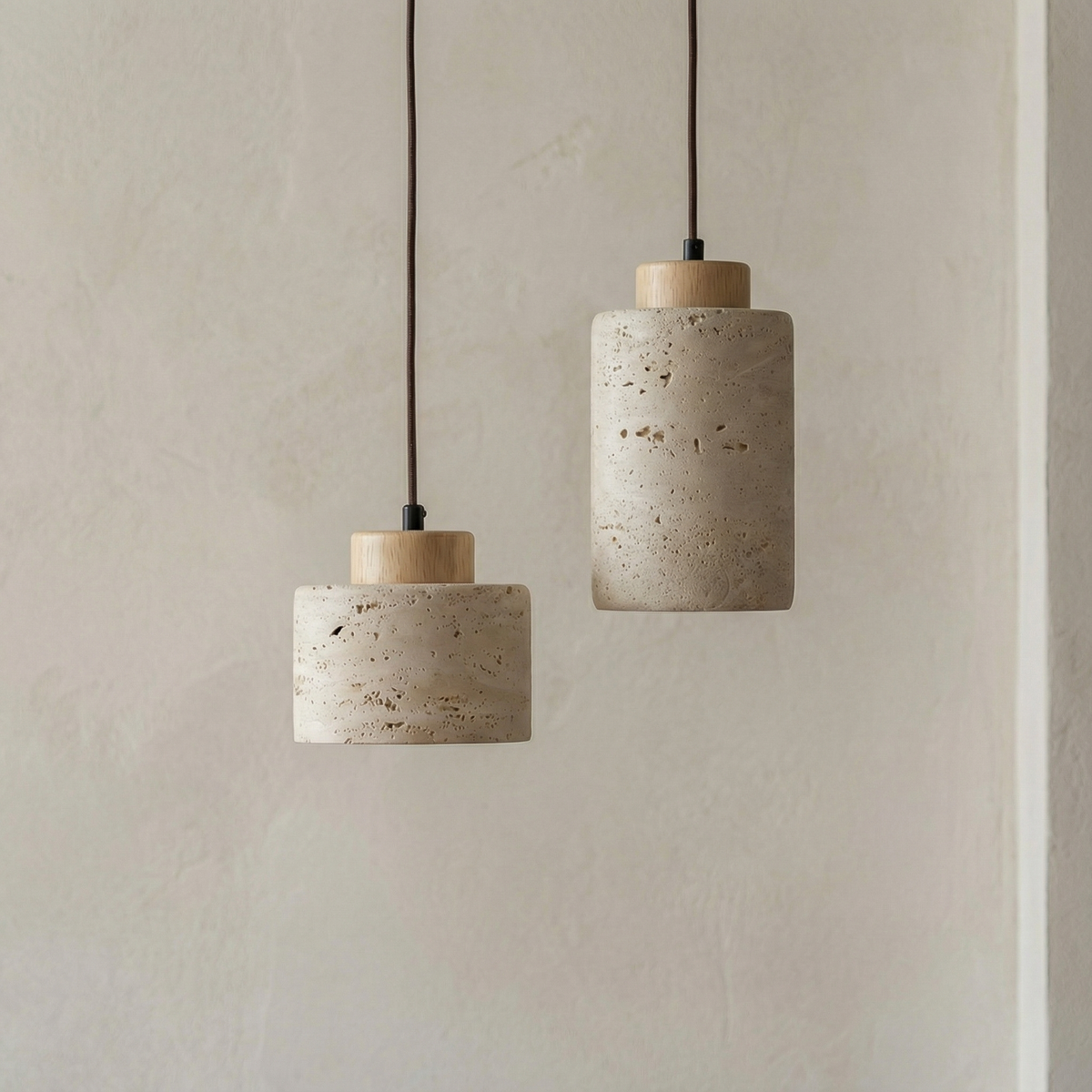 Two stone pendants with light wood caps against a pale wall