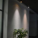 Two cylinder ceiling lights washing warm light down a grey wall