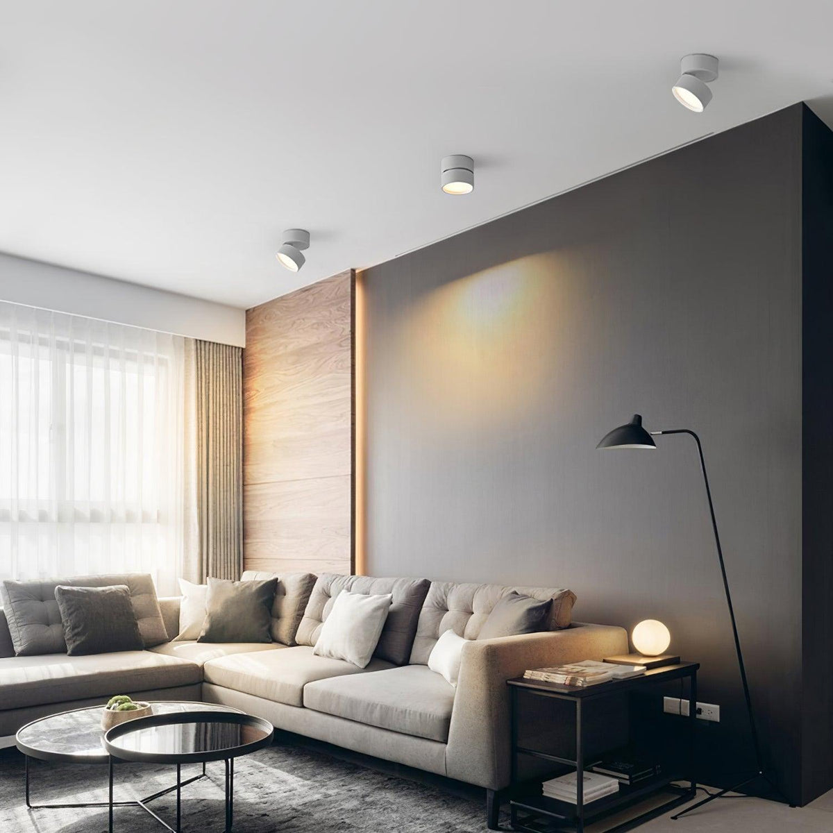 Surface mounted spot lights on a white ceiling above a grey corner sofa