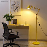 White swing arm floor lamp standing in a home office reading corner