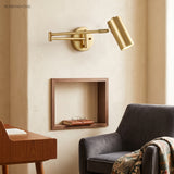 Gold swing arm sconce lit above a wall niche and a desk