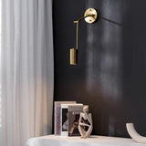 Gold swing arm sconce lit against a dark wall beside a curtain
