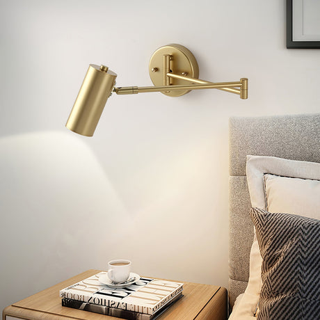 Gold swing arm sconce lit above a bedside table and coffee cup
