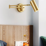 Gold swing arm sconce lit beside a wooden headboard