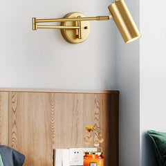 Gold swing arm sconce lit beside a wooden headboard