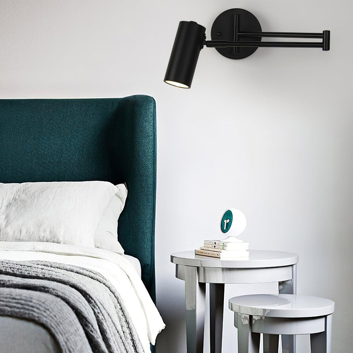 Black swing arm sconce lit beside a green upholstered headboard