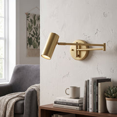 Gold swing arm wall sconce extended over a side table and books