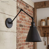 Black iron swing arm sconce mounted on a painted brick wall