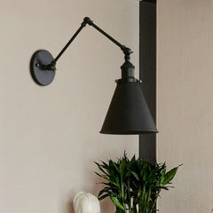 Black swing arm sconce beside a dark post and a potted plant