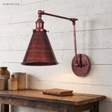 Rust iron swing arm sconce on white boards above a timber table