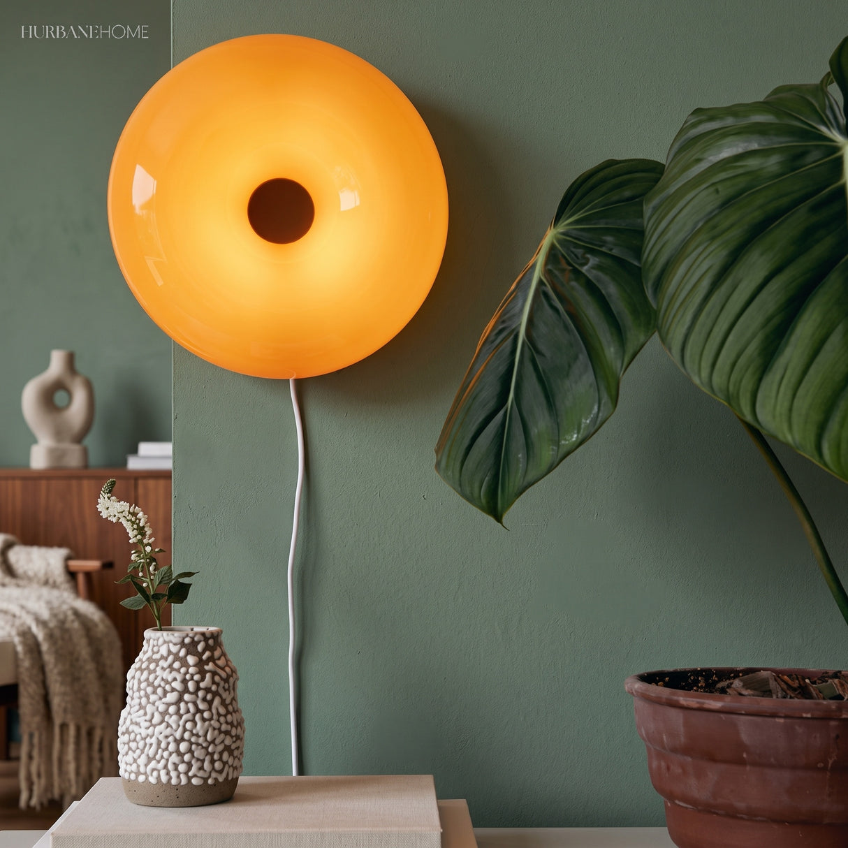 Amber donut glass lamp on a console by a green wall