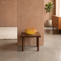 Amber donut glass lamp on a wooden stool