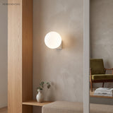 Frosted glass globe wall lamp in an entry nook beside a timber bench