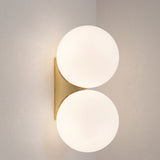 Double frosted glass globe wall lamp with gold bracket on a plain wall