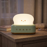 Green toaster table lamp casting warm light on a wooden desk