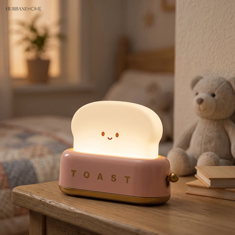 Pink toaster table lamp lit beside a teddy bear in a nursery