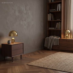 Gold dome table lamp on a walnut sideboard in a plain grey walled room