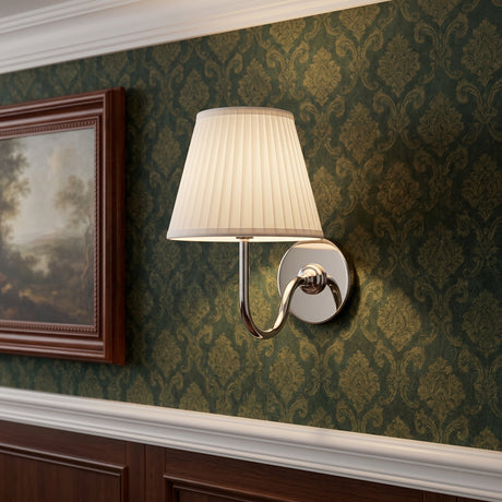 Polished chrome wall sconce with pleated white linen shade on patterned wall