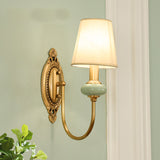 Single gold sconce lit warm on a pale green painted wall