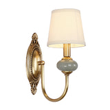 Single gold sconce with a ceramic accent shown on plain white