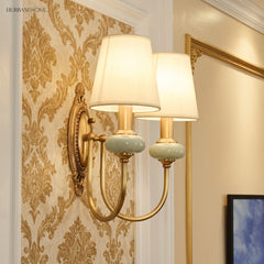Two light gold sconce lit against gold damask wallpaper