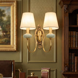 Two light gold sconce lit in a green library beside a bookcase