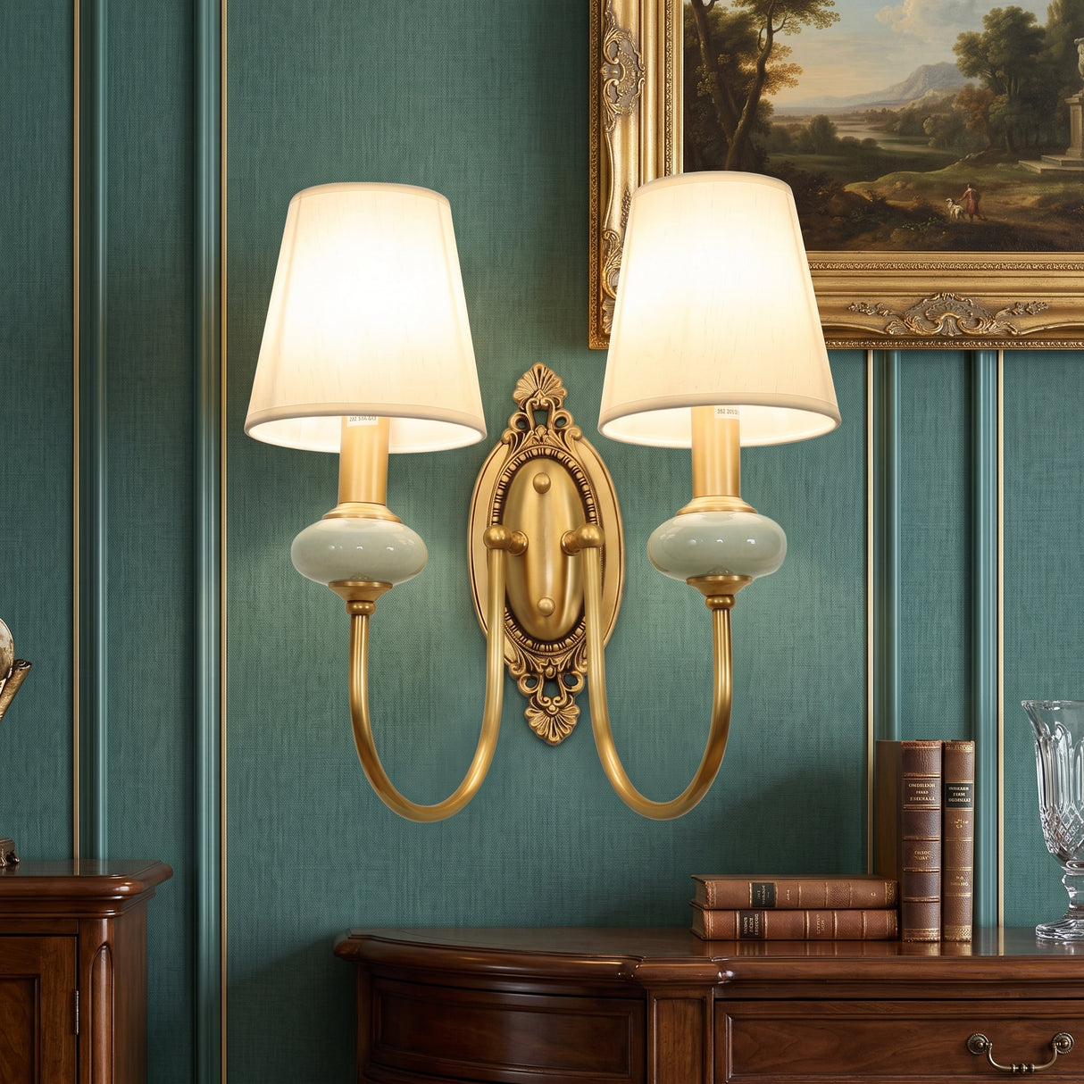 Two light gold sconce with white fabric shades on a green wall
