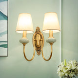 Two light gold sconce on a green wall above white lilies