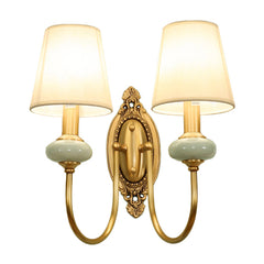 Two light gold sconce with both shades lit on plain white