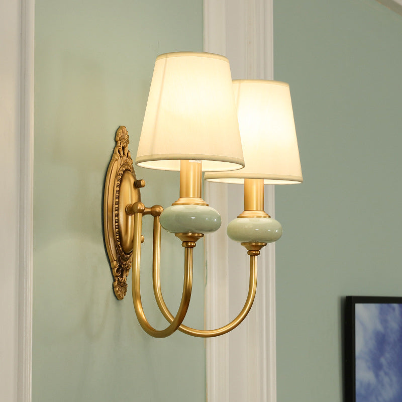 Two light gold sconce on a pale wall beside a white picture frame