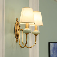 Two light gold sconce on a pale wall beside a white picture frame