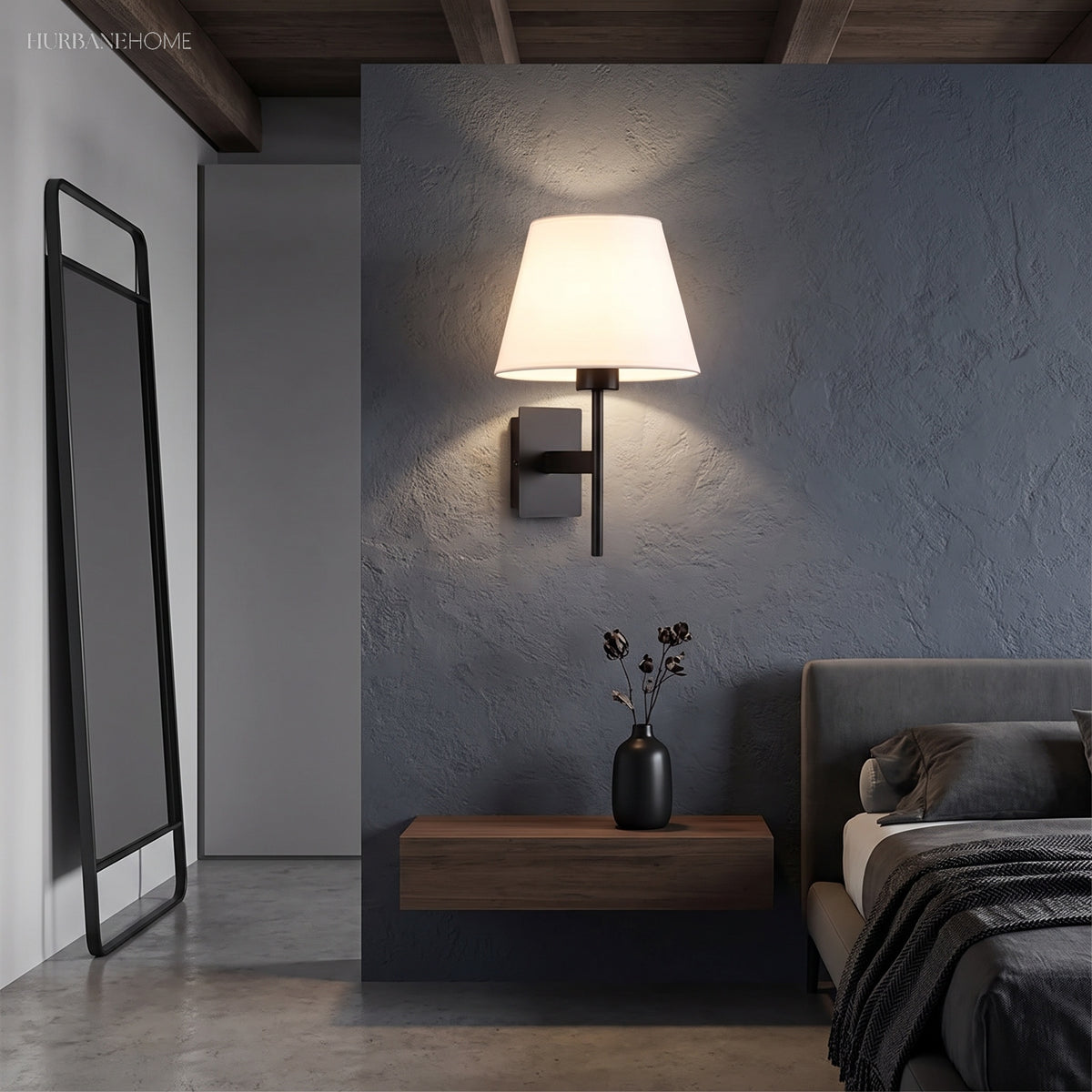 Wall sconce lighting a bedroom above a floating nightstand beside a made bed