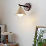 Travertine cone shade wall sconce lit warm on a neutral wall