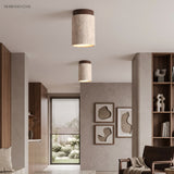 Pair of travertine ceiling lights above a neutral seating and shelving area
