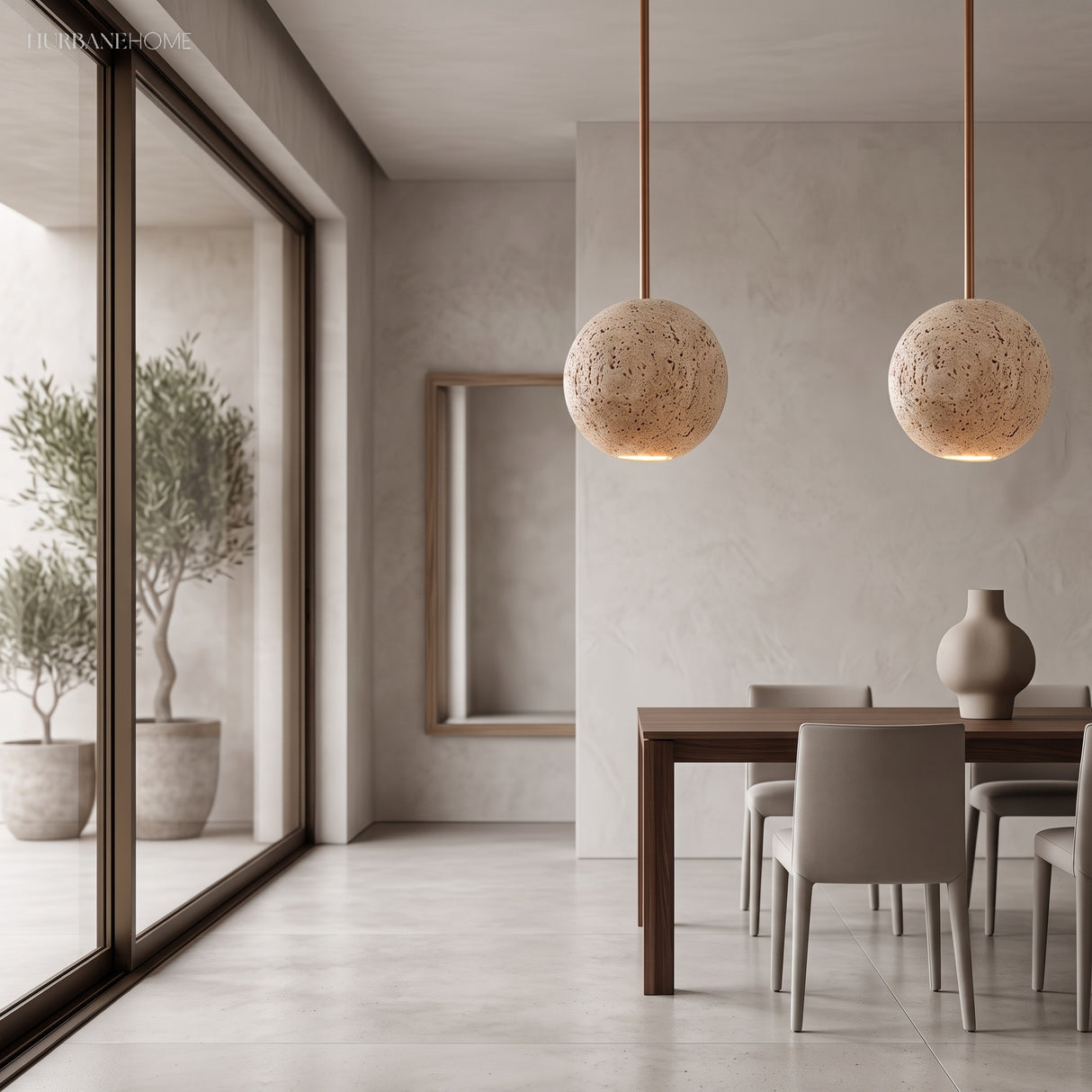 Pair of travertine ball pendants above a dining table by tall windows