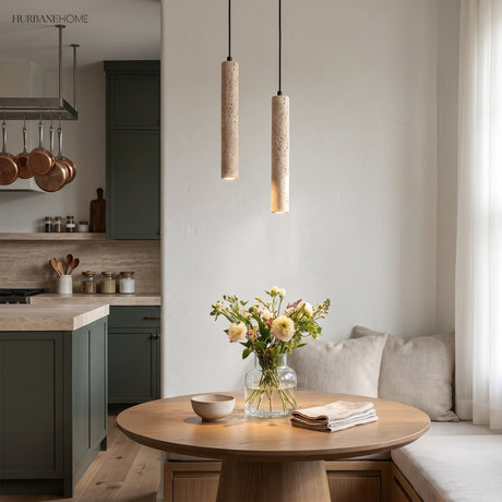 Two travertine cylinder pendants above a round table in a green kitchen