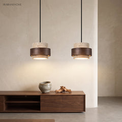 Two travertine and wood pendants above a low dark wood sideboard and vases