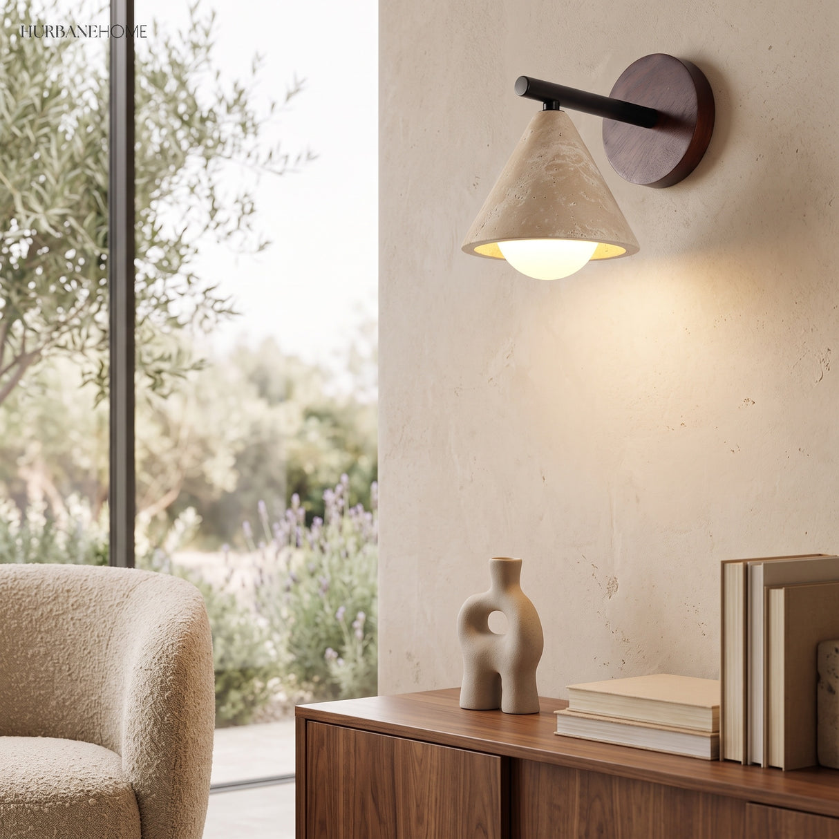 Stone wall sconce glowing warm beside a window and boucle chair
