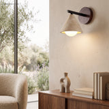 Stone wall sconce glowing warm beside a window and boucle chair